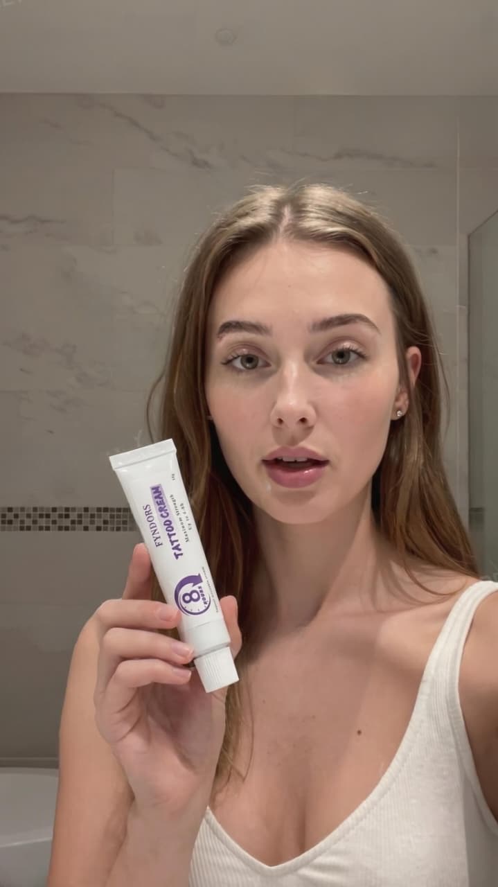 Tattooed model holding FYNDORS numbing cream